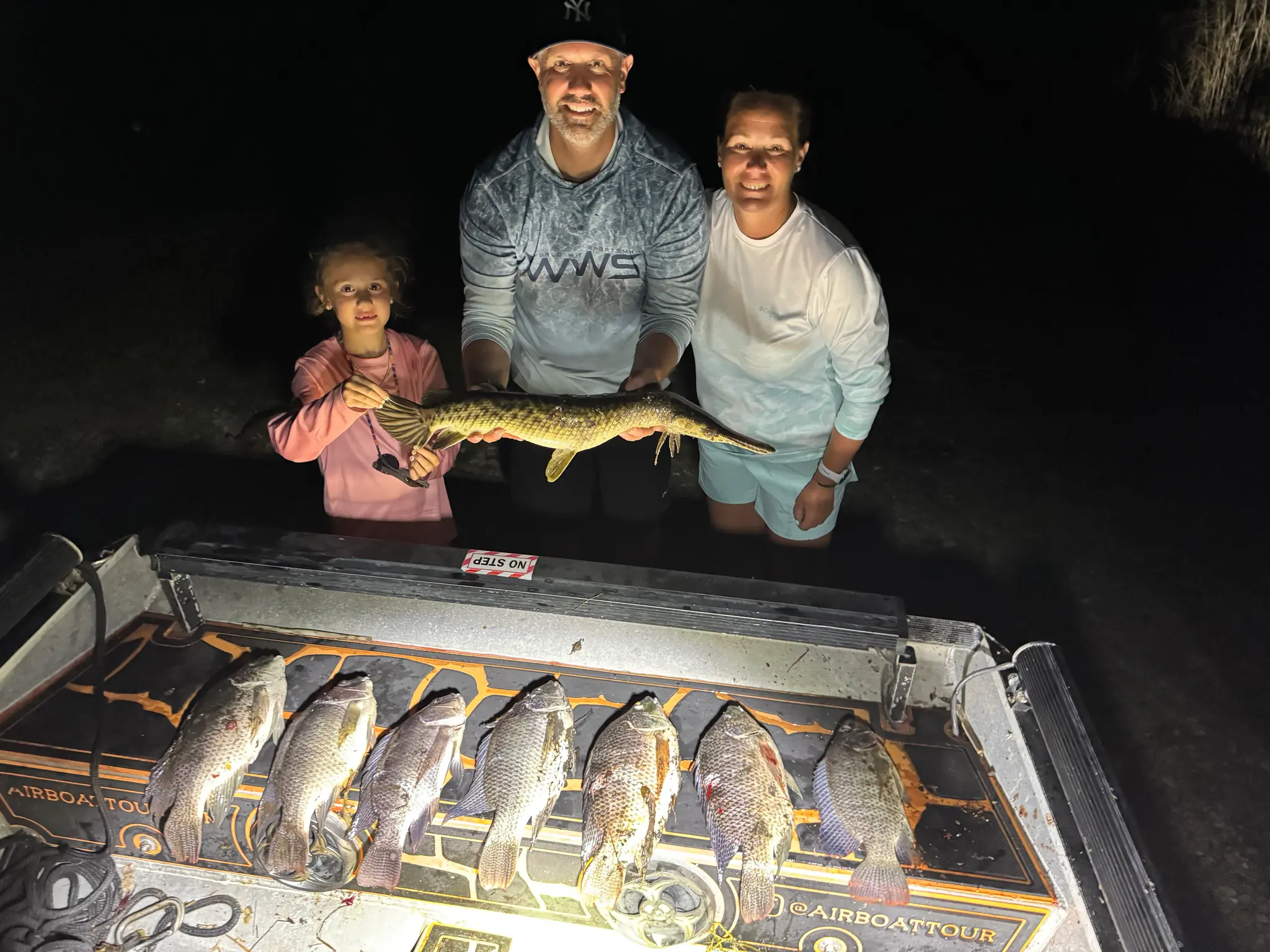 A person holds a vibrant yellow fish with orange accents, showcasing its colorful scales while seated on a boat